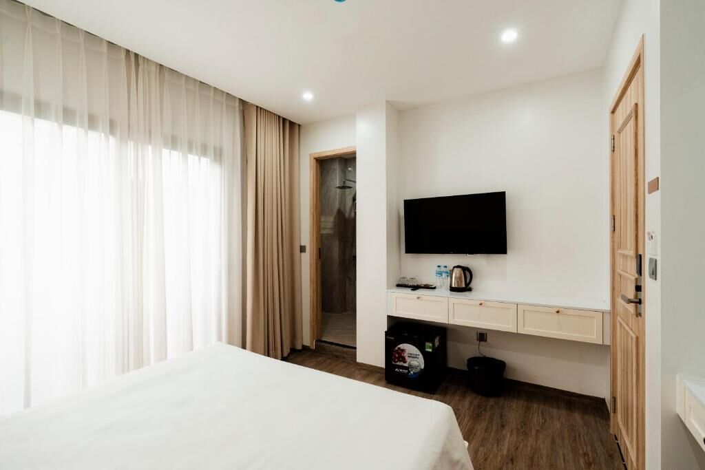Een hotelkamer met een bed, een televisie, een bureau met waterkoker en een kledingkast.