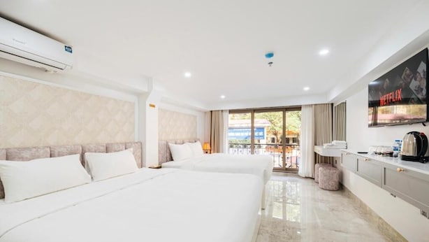 A hotel room with two beds, a TV, a minibar, and a view of the outside. - Hanoi Serenity Hotel (Hanoi)