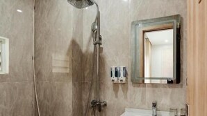 A bathroom with a shower, sink, mirror, and toilet. - Hanoi Serenity Hotel (Hanoi)