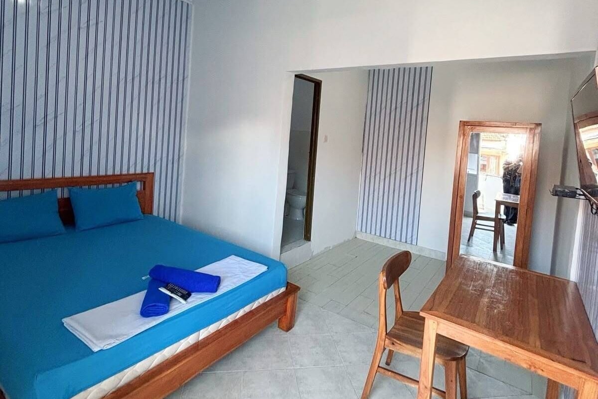 A bedroom with a bed, a wooden table, and a chair.