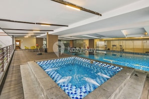 An indoor swimming pool with a tiled floor and a separate hot tub area. - Girava by Kozystay - Dago (Bandung)