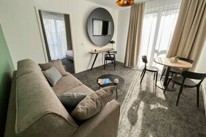 Una sala de estar moderna con sofá, mesa de centro, televisor y comedor.