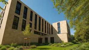 Un bâtiment moderne doté d’une cour intérieure, comprenant un chemin central, un petit arbre et une pergola.