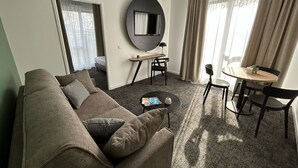 Un salon moderne avec un canapé, une petite table ronde et un téléviseur fixé au mur.