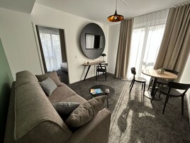 Una sala de estar moderna con un sofá, una mesita redonda y un televisor montado en la pared.