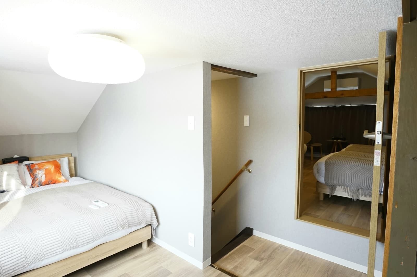 A bedroom with a bed, a mirror, and a door leading to another room.
