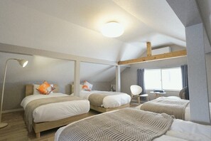 Ein Schlafzimmer mit zwei Betten, einem Schreibtisch, einem Sessel und einem großen Fenster.