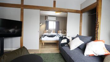 Una habitación de hotel moderna con cama, sofá, televisor y estructura de techo de madera.