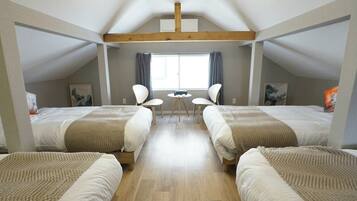 A room with two beds, a small table, two chairs, and a window with curtains.