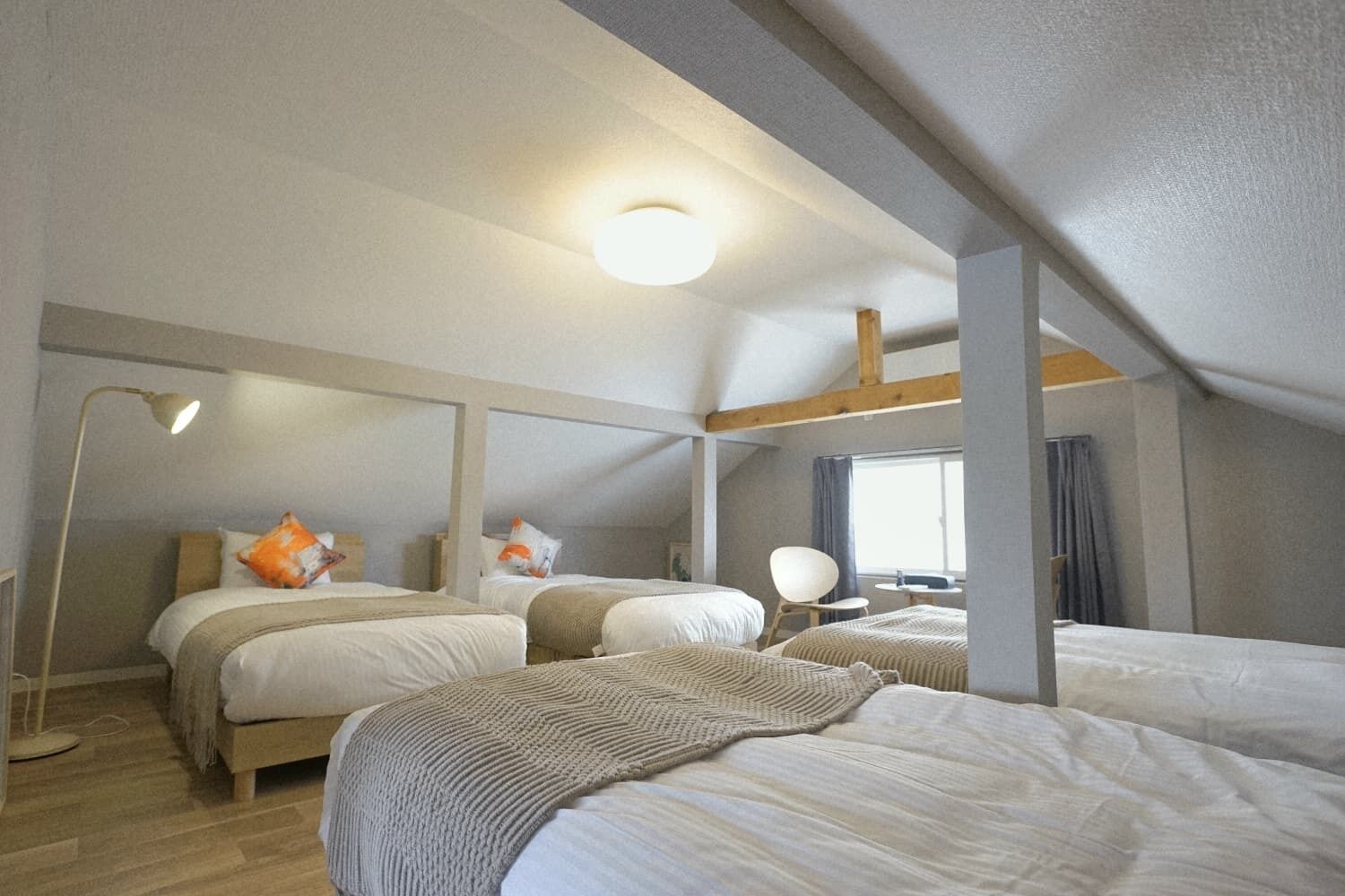 Een slaapkamer met twee bedden, een nachtkastje, een lamp en een raam.