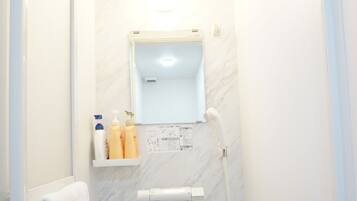 Un baño pequeño y moderno con ducha, un espejo y un estante con artículos de aseo.