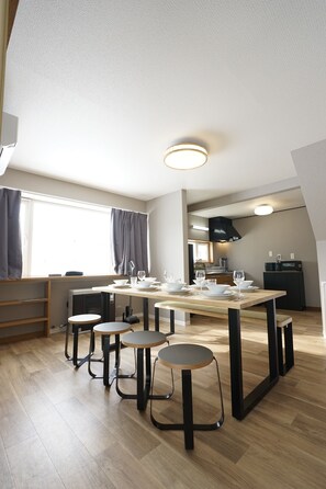 Una cocina moderna con una mesa de comedor para cuatro personas, horno empotrado y ventana con cortinas.
