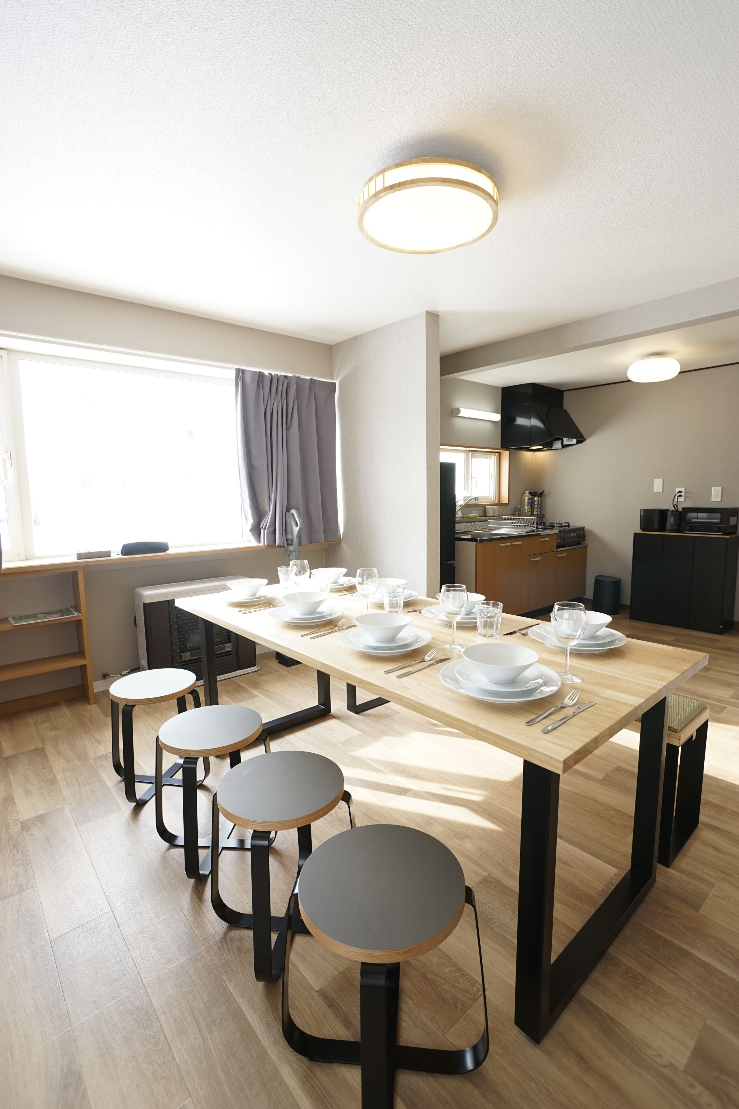 Une cuisine moderne avec une table à manger pour quatre personnes, un four encastré et une fenêtre avec des rideaux.