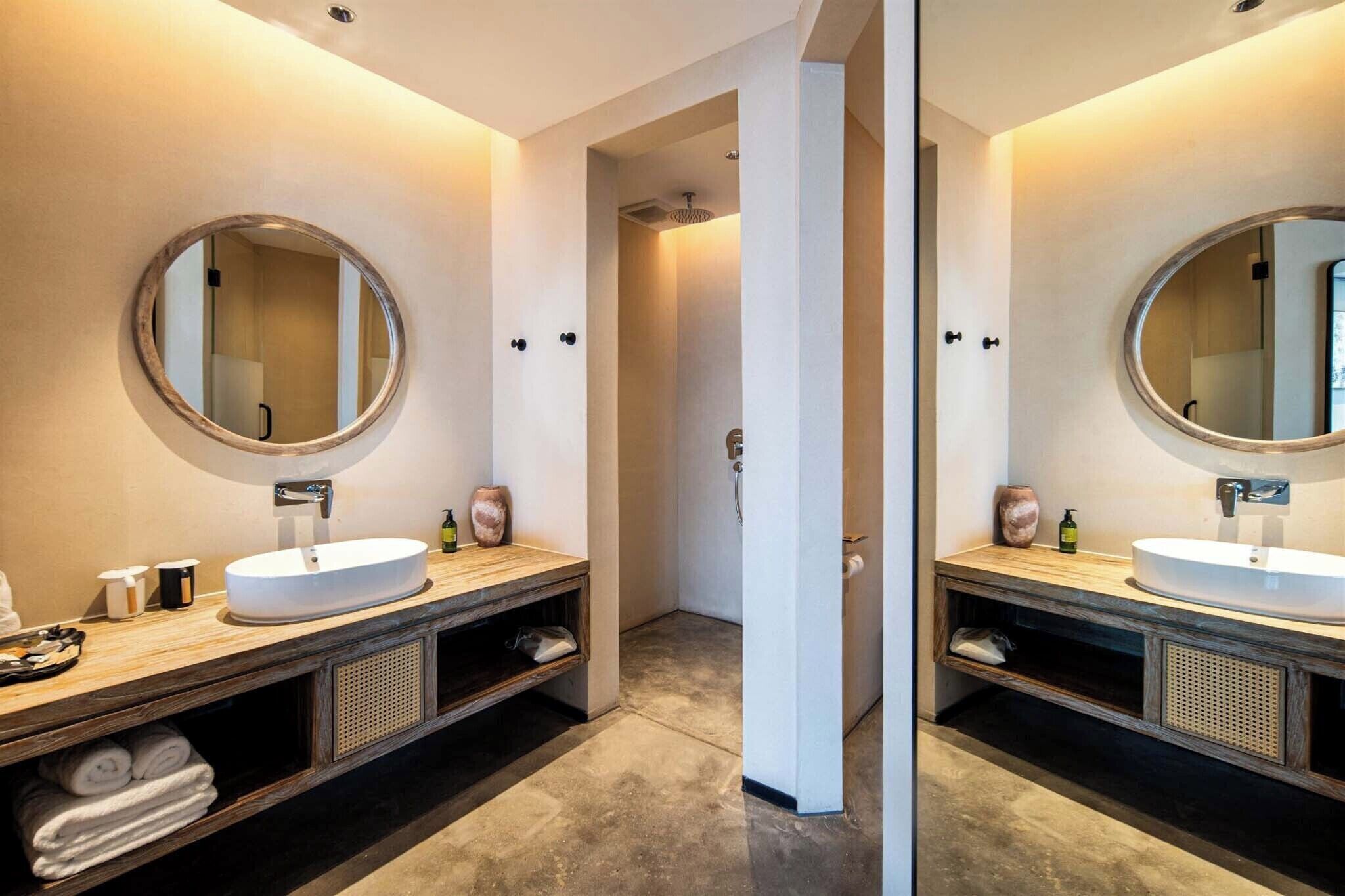 Ein modernes Badezimmer mit zwei Waschbecken, einem Spiegel und einer Dusche.