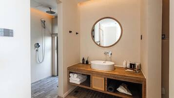 Un baño moderno con un mueble de tocador de madera, un espejo redondo y una ducha.