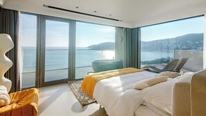 A modern bedroom with a large bed, a seating area, and a view of the sea. - XIHUI Cliff Hotel (Zhoushan)