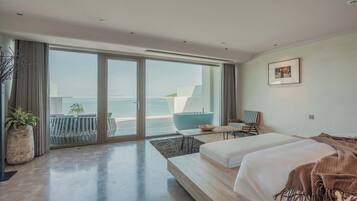Een moderne hotelkamer met een grote schuifpui naar het balkon, een bed, een kleine tafel en een stoel.