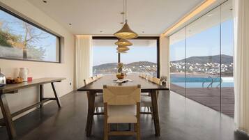 A modern dining room with a long table, chairs, and a hanging light fixture.