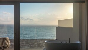 A balcony with a view of the sea, a large bathtub, and a small table. - XIHUI Cliff Hotel (Zhoushan)