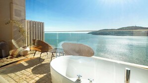 A balcony with a view of the sea, a bathtub, wicker chairs, and a potted plant. - XIHUI Cliff Hotel (Zhoushan)