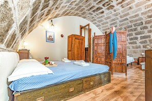 A bedroom with a wooden bed, a nightstand, a wardrobe, and a decorative wooden partition. - Fort Galantè, Alghero, Italy (Alghero)