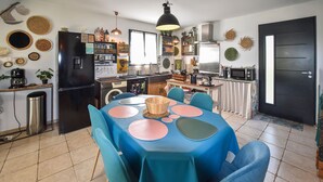 Una cucina con un tavolo da pranzo apparecchiato per quattro persone, un frigorifero nero e diversi elettrodomestici.