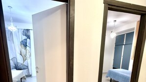 Deux pièces avec des sols carrelés, un lit, une armoire et un luminaire suspendu.