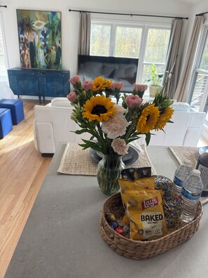 A living room with a sofa, a coffee table, a vase with flowers, a television, and a blue cabinet. - Cozy Studio Downtown Raleigh (Raleigh)