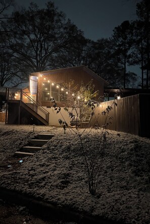 A modern house with a wooden exterior, a staircase leading to a deck, and string lights. - Cozy Studio Downtown Raleigh (Raleigh)
