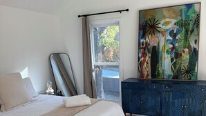 Ein Schlafzimmer mit einem Bett, einem Schminktisch, einem Bild und einem Fenster.