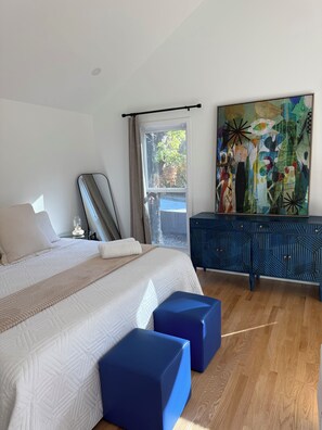 A bedroom with a bed, a dresser, a painting, and a window. - Cozy Studio Downtown Raleigh (Raleigh)