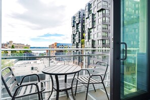 Ein Balkon mit Tisch und Stühlen mit Blick auf eine Stadtlandschaft und modernen Gebäuden.