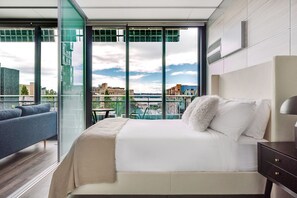 Ein modernes Hotelzimmer mit einem großen Bett, einer Couch und einem Balkon mit Blick auf die Stadt.