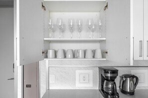 Una cocina con un espacio para vinos empotrado que contiene varios vasos y una cafetera sobre la encimera.