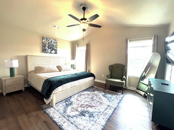 A bedroom with a bed, a standing lamp, a chair, a ceiling fan, and a large window. - Spacious Home Near HSV Airport & Entertainment - Space & Rckt, Orion amp theatre (Madison)