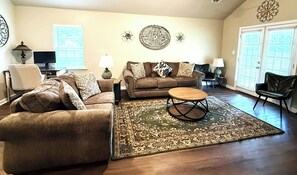 A living room with a brown sofa, a coffee table, and a patterned rug. - Spacious Home Near HSV Airport & Entertainment - Space & Rckt, Orion amp theatre (Madison)