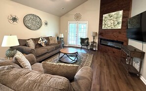 A living room with a sofa, a coffee table, decorative wall art, a fireplace, and a television.