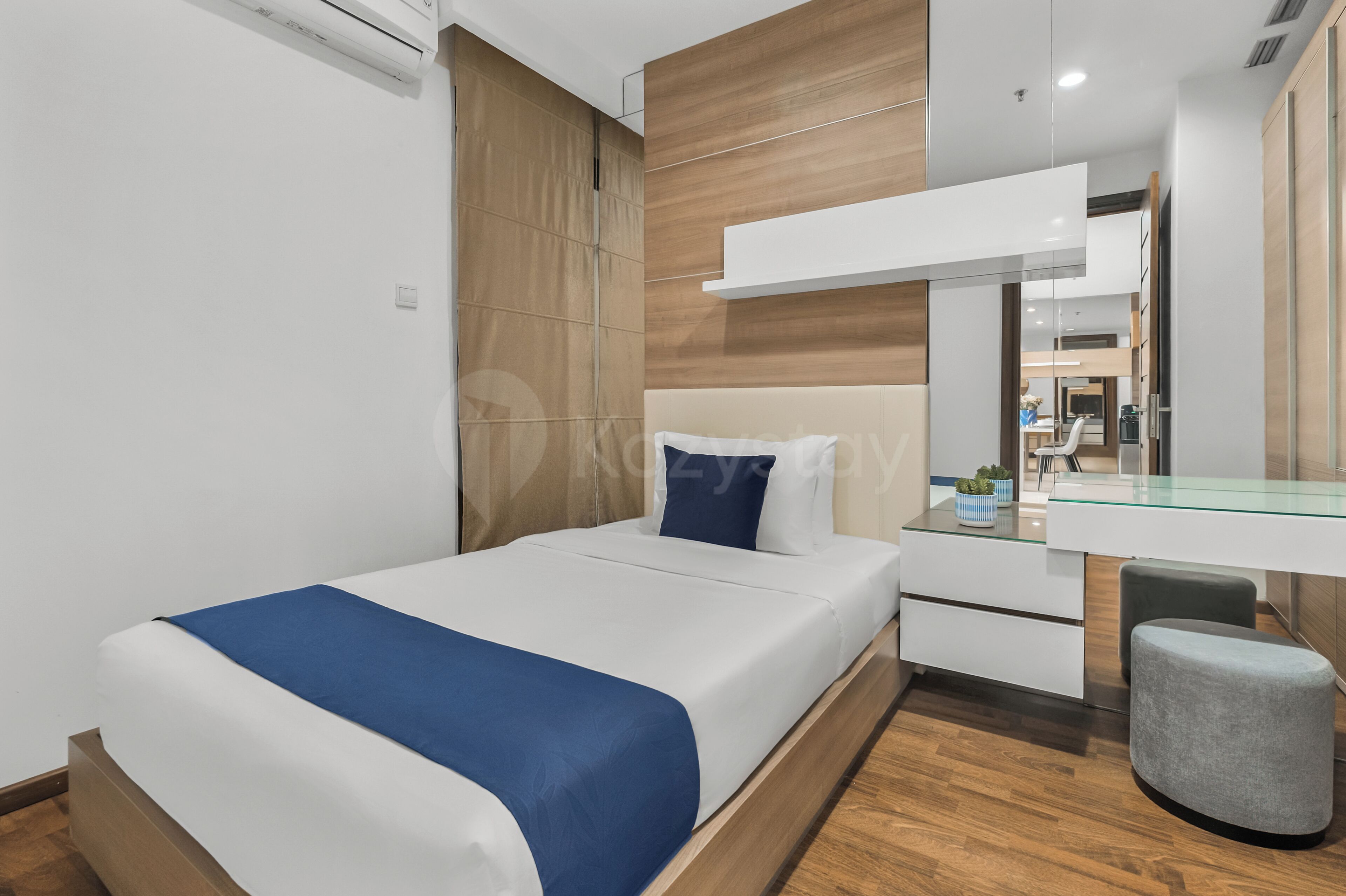 A modern hotel room with a bed, a desk, a chair, and a mirror.