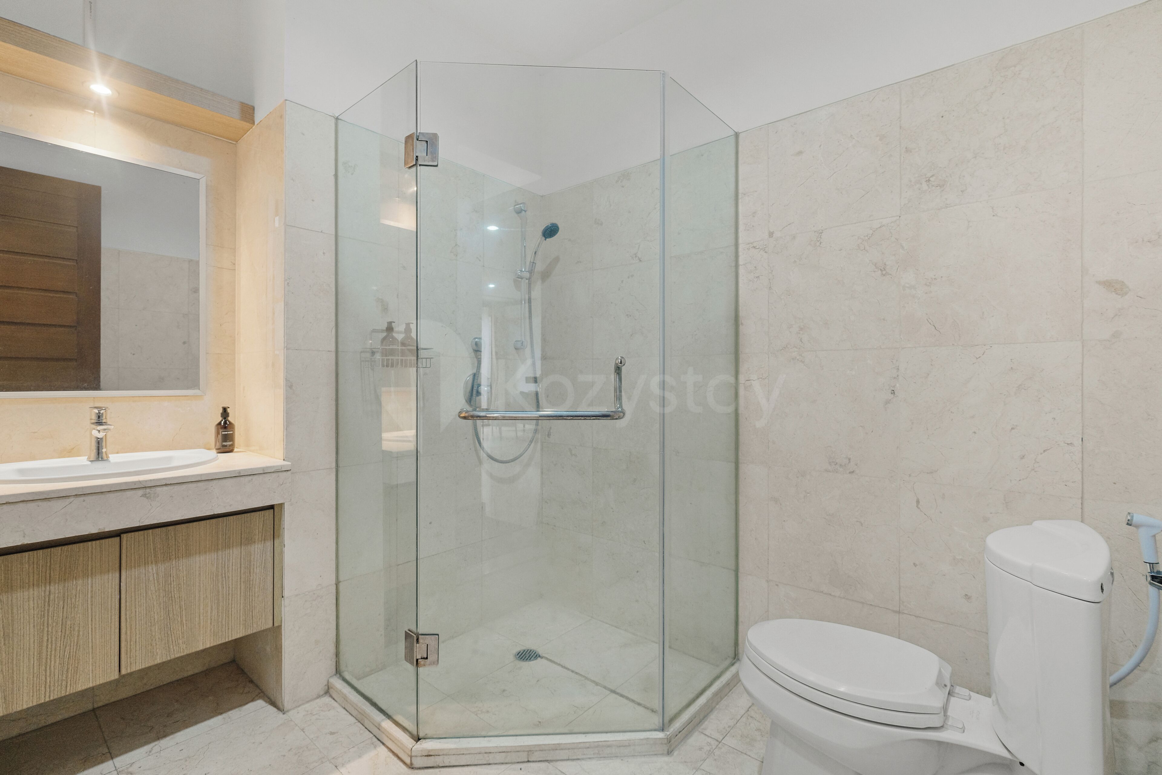 Un baño moderno con cabina de ducha de vidrio, inodoro blanco y tocador de madera.
