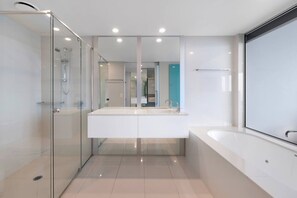Une salle de bain moderne avec une douche à parois de verre, un grand meuble-lavabo blanc et une baignoire.