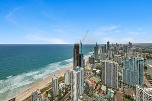 Un paysage urbain côtier avec de hauts immeubles, une plage et une grue de construction.