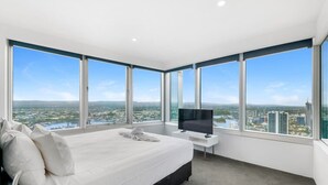 A modern hotel room with a large bed, a flat-screen TV, and a city view. - Oversized South-Facing Apartment | Q1 Level 39 (Surfers Paradise)