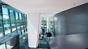 A modern interior with a glass facade, a central column, and a seating area. - Oversized South-Facing Apartment | Q1 Level 39 (Surfers Paradise)