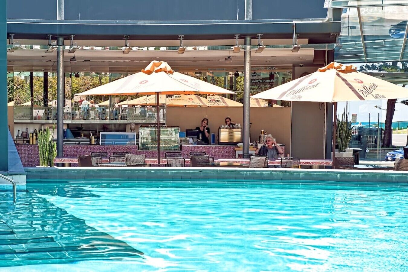 A poolside area with umbrellas, lounge chairs, and a bar.