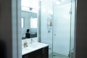 A modern bathroom with a glass shower enclosure, a white sink, and a large mirror. - Lake Getaway in Barrie (Barrie)