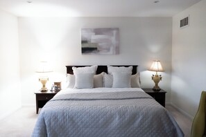 A bedroom with a bed, two bedside tables with lamps, a wall-mounted abstract painting, and a headboard. - Lake Getaway in Barrie (Barrie)