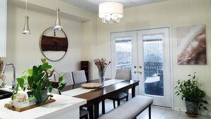 A modern kitchen with a dining area, a chandelier, and a view through a glass door. - Lake Getaway in Barrie (Barrie)