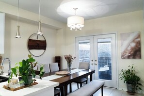 A modern kitchen with a dining area, a chandelier, and a view through a glass door. - Lake Getaway in Barrie (Barrie)
