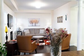 A living room with a sofa, chairs, a coffee table, and a vase with flowers. - Lake Getaway in Barrie (Barrie)
