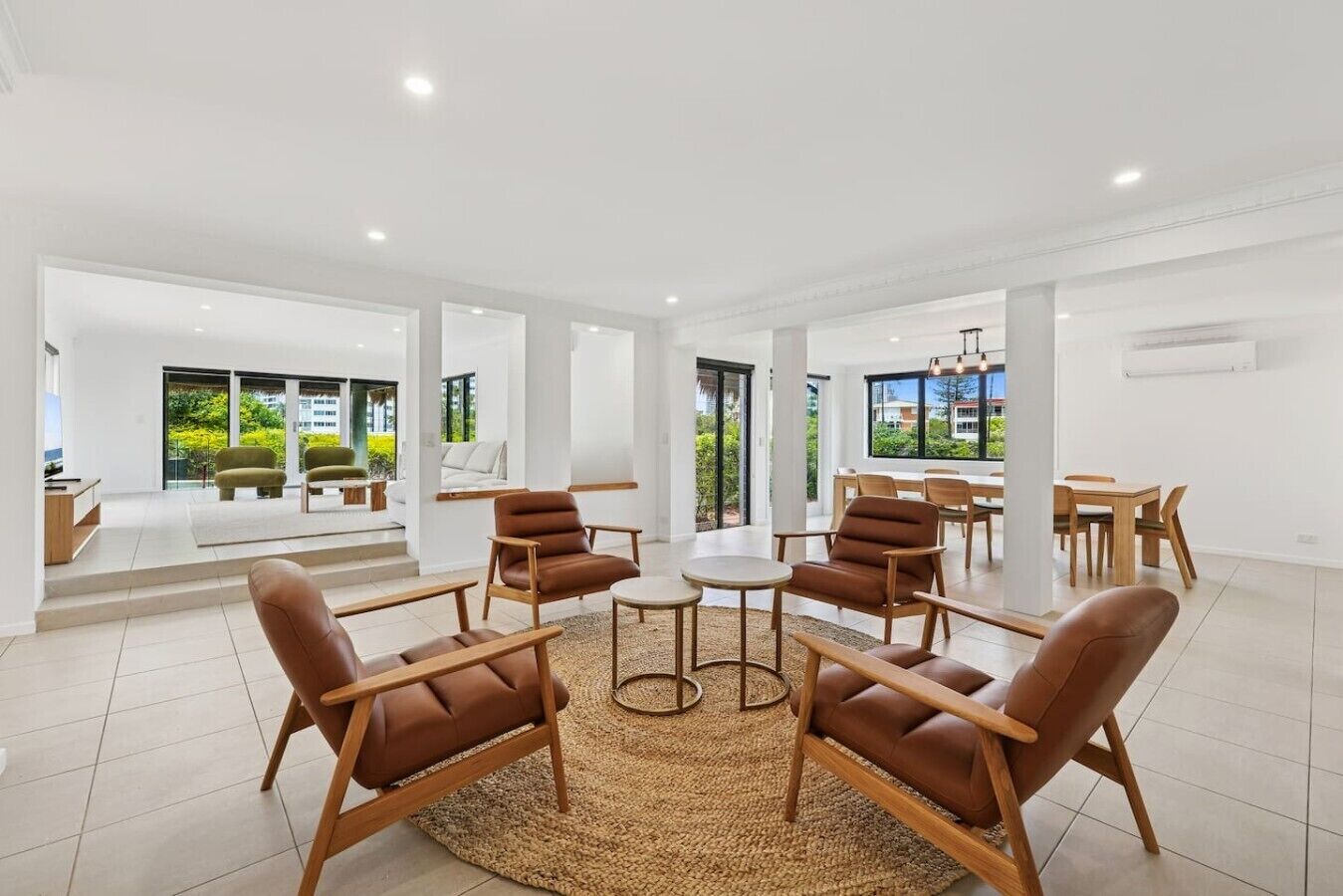 A spacious living area with a central coffee table, multiple seating options, and large windows offering views of the outdoors.